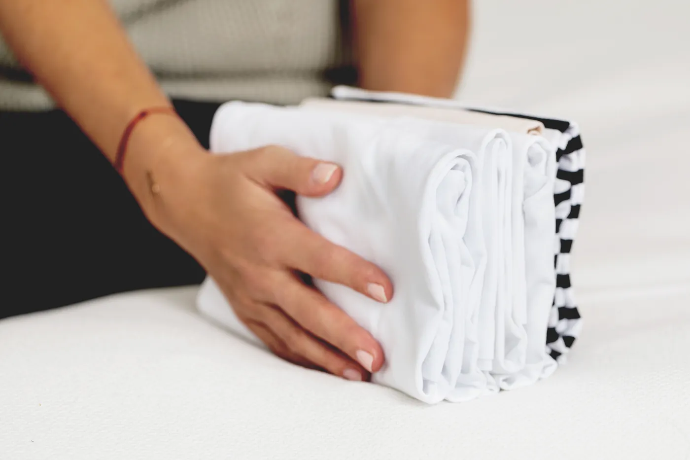Hands holding a neat stack of shirts folded the KonMari way